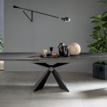 Photo d'une table avec rallonge intégrée. Pied central en V. Table avec plateau céramique noir veine blanche et rallonge gris anthracite.